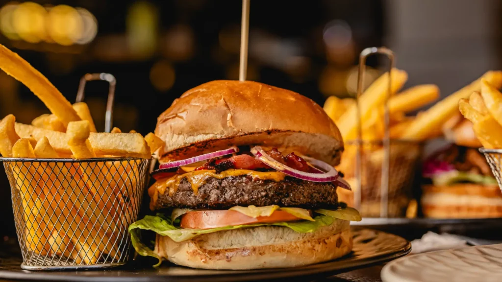 Soczysty burger z wołowiną, świeżymi warzywami, cheddar i chrupiącymi dodatkami, podany na domowej bułce w restauracji Just Friends na Starym Rynku w Poznaniu.